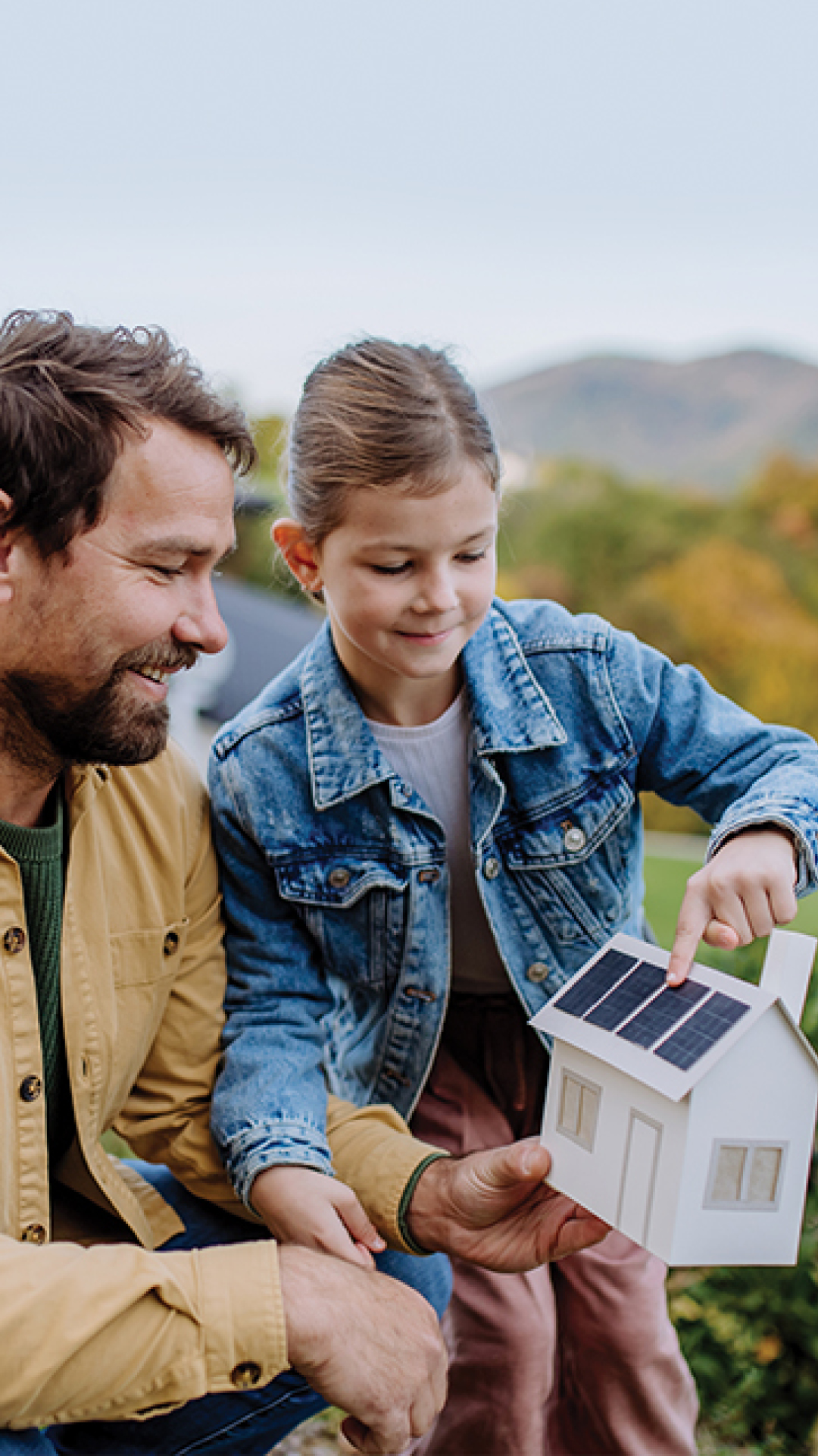 Man and girl holding solar panel tiny house.